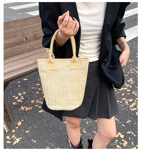 Detailed herringbone weave pattern on light beige straw bucket tote bag for autumn