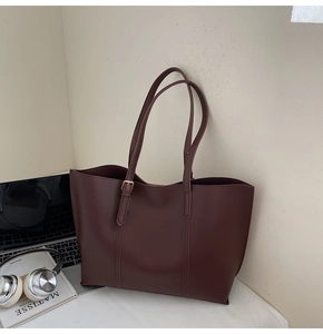 Détail du grand sac cabas marron foncé avec coutures verticales sur bureau blanc