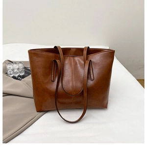 Detail view of large brown PU leather tote bag with vertical stitching and slim straps