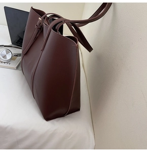 Détail du sac cabas en cuir marron foncé montrant la bandoulière et la boucle en métal