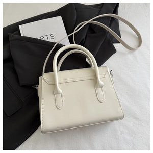 Detail of cream minimalist handbag with smooth texture and sturdy dual top handles