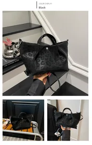 Detail view of black leopard print tote with cylindrical handles and detachable strap