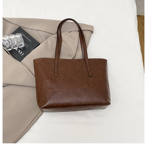 Detail of a large retro dark brown tote bag with matte texture and dual long handles
