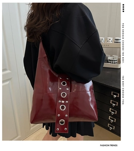 Detail of burgundy glossy leather shoulder bag with metallic eyelets on the strap