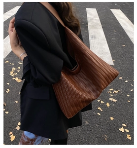 Detailed view of large brown woven leather tote bag texture and street style look