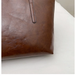 Detailed view of the neat stitching and vintage faux leather texture on the tote bag