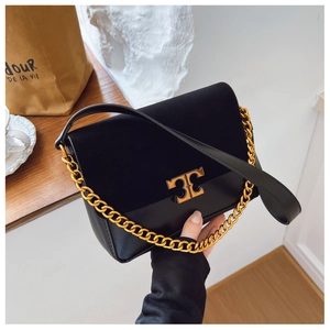 Close-up of black leather handbag featuring suede flap and gold metal logo hardware
