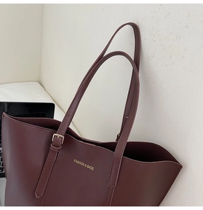 Détail du cabas en cuir bordeaux avec texte doré gaufré et bandoulière réglable pratique