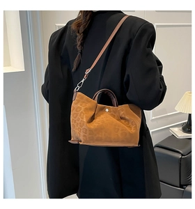 Detail of leopard print tote bag featuring textured suede fabric and premium brown leather straps