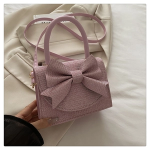 Detailansicht der rosa Glitzer-Handtasche mit großer dekorativer Schleife und Metallkette