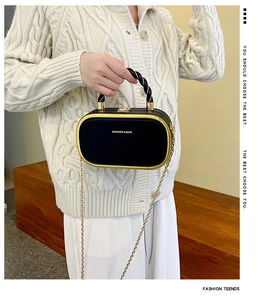 Detail of black leather capsule bag with gold metal frame and twisted rope handle