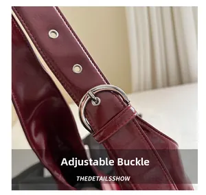Close-up of adjustable dark red leather strap with silver buckles and metal eyelets