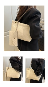Detail view of cream chain tote bag set featuring repeating embossed patterns and gold links