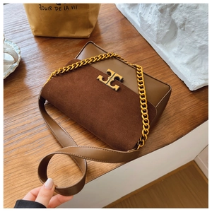 Close-up of vintage brown leather handbag with gold metal logo and suede texture