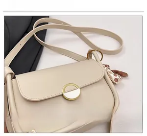 Detail view of beige crossbody bag with gold round buckle and decorative silk scarf