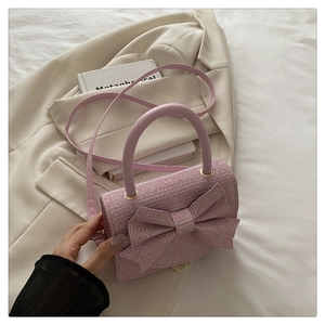 Detailansicht einer rosa gewebten Mini-Handtasche mit Schleife und Perlglanz-Oberfläche