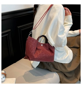 Detail of burgundy leopard print tote bag with metallic buckle on soft textured fabric