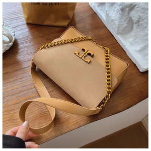 Detail view of mustard yellow leather bag showing gold T-logo and chain strap texture