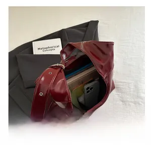 Top view of spacious burgundy patent leather tote bag interior with silver eyelet straps