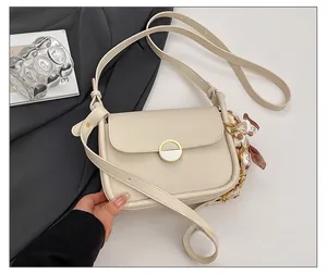 Detail of cream shoulder bag with round metal lock and decorative printed silk scarf