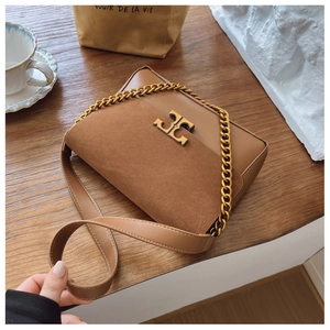 Close-up of brown leather bag with golden metallic logo and chain strap on wood