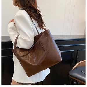 Deep brown faux leather tote bag with long handles shown on a model's shoulder
