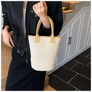 Detailed close-up of woven herringbone texture and bright yellow handle on bucket bag