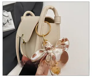 Detail of cream leather shoulder bag with gold ring hardware and polka dot scarf