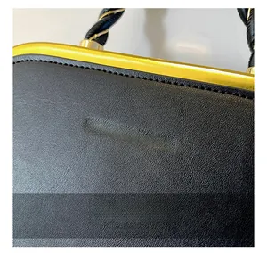 Detail of black lychee leather handbag with golden frame and embossed logo