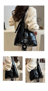 Detail of glossy black punk shoulder bag with large silver metal eyelets and rivets
