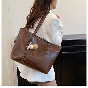 Detail of vintage brown oil wax leather tote with a baseball glove keychain accessory