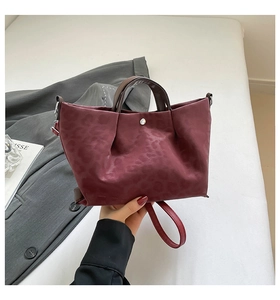 Close-up of burgundy leopard print handbag with metallic button and sleek brown handle
