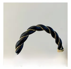 Detail of twisted black leather and gold metal chain handle with elegant square lock