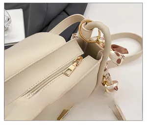 Close-up of cream leather handbag with smooth gold zipper and floral silk scarf detail