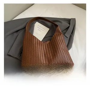 Detail view of brown woven shoulder bag with hobo silhouette on grey blazer