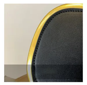 Macro detail of black lychee grain leather with golden metal frame and stitching