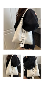 Detail of white hobo bag showing wide shoulder strap with silver eyelets and studs
