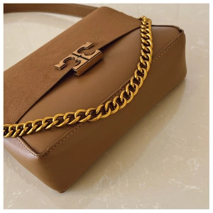 Detailed side view of brown leather bag with golden T-shaped clasp and chain detail