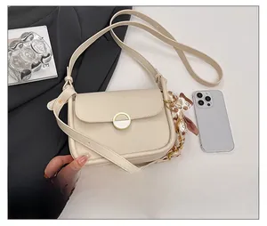 Detail of a creamy white PU leather crossbody bag featuring a gold buckle and floral silk scarf