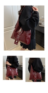 Detail of burgundy patent leather shoulder bag with metallic eyelets and glossy finish