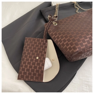 Detail of brown tote bag set with logo print and gold chain strap showing interior space