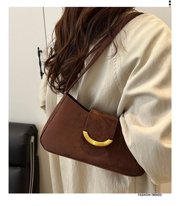 Close-up of suede shoulder bag featuring a half-moon gold buckle and rich texture