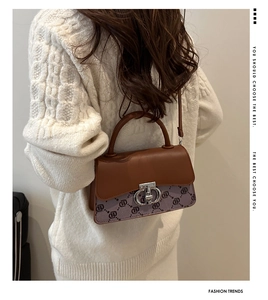 Brown leather and purple canvas crossbody bag with silver twist lock on a white sweater