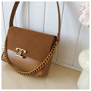 Close-up of brown suede and smooth leather shoulder bag with golden chain and logo