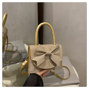 Detailansicht der champagnergoldenen Abendtasche mit Schleife und funkelndem Strass
