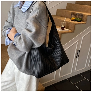 Close-up of black woven large shoulder bag showing detailed V-shaped texture and faux leather