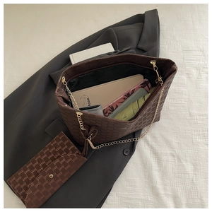 Macro view of brown monogram tote bag showing large interior space for books and umbrella