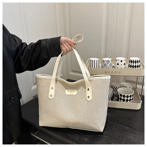 Close-up of cream canvas tote bag with leather trim and elegant brand name metal plate