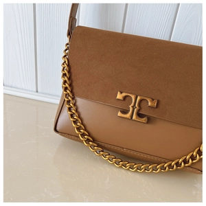 Detail of brown leather and suede shoulder bag featuring a gold chain and vintage metal buckle