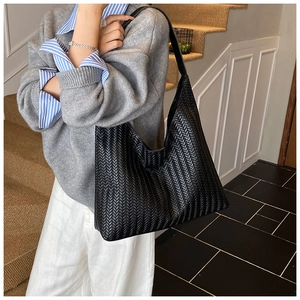 Close-up of a black woven leather hobo bag with a minimalist shoulder strap design